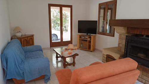 a living room with a couch a chair and a tv at Villa du Moulin vers la Mer in Fleury
