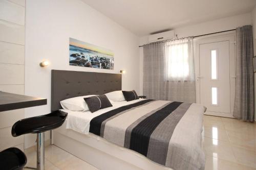 Un dormitorio con una cama con una manta blanca y negra. en Apartments Karamarko, en Baška