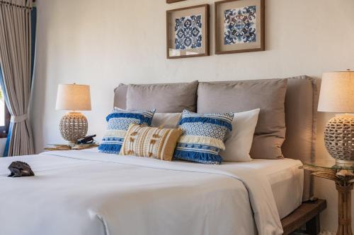 a bed with blue and white pillows and two lamps at Aleenta Hua Hin - Pranburi - The Small Luxury Hotels of the World in Pran Buri