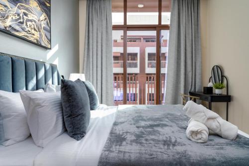 a bedroom with a bed with white pillows and a window at White Sage New Large 1BR at JVC in Dubai