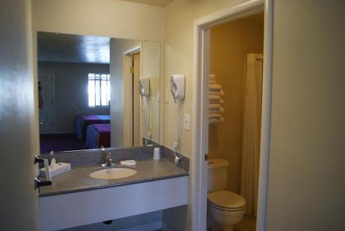 a bathroom with a sink and a toilet and a mirror at Travelers Motel in Cottonwood