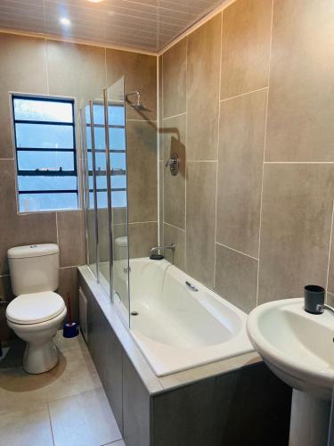 a bathroom with a tub and a toilet and a sink at Cozy Livin - Duplex in Maseru