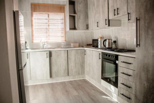 a kitchen with white cabinets and a sink and a stove at Cozy Livin - Duplex in Maseru