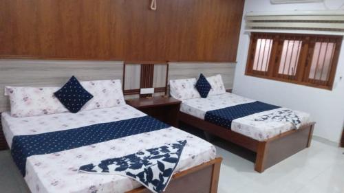 a bedroom with two beds with blue and white sheets at Hotel SU kataragama in Kataragama