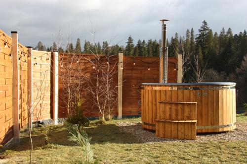 a wooden fence and a hot tub in a yard at Domek z balią - Dotyk Motyla in Łapsze Niżne