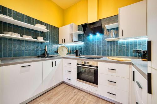 a kitchen with white cabinets and green tiles at Grand Central Station 2 Bed Apartment A1 in Glasgow