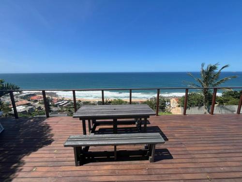 a picnic table and bench on a deck with the beach at The Windsock in Ballito