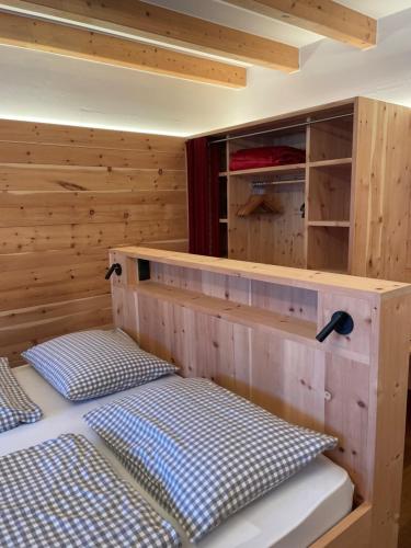 a bed in a room with a wooden wall at Hotel Schopfenhof in San Candido