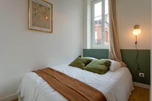 une chambre avec un lit avec deux oreillers dessus dans l'établissement Le Tisserand - Appartement Cosy proche de la Gare, à Toulouse