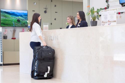 a woman with a bag of luggage at a counter at JR Hotels Gate 7 Bologna in Calderara di Reno