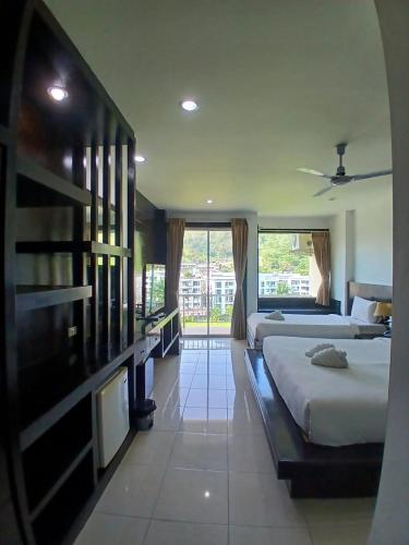 a bedroom with two beds and a large window at SM Patong Resort in Patong Beach