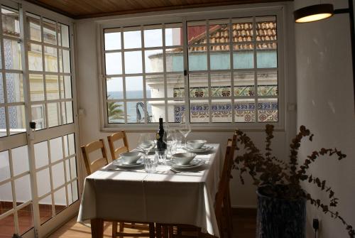 a dining room with a table with a bottle of wine at Plage,15 m, mer, Casa Melissa by SesimbraSunSea in Sesimbra
