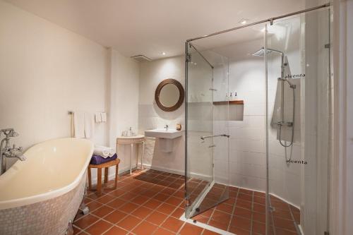 a bathroom with a tub and a glass shower at Aleenta Hua Hin - Pranburi - The Small Luxury Hotels of the World in Pran Buri