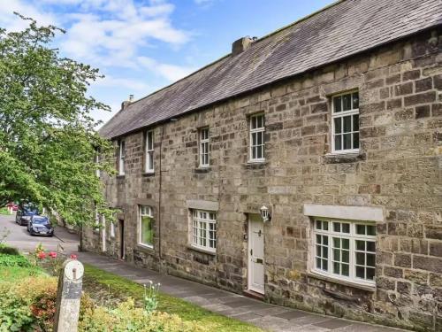 an old stone building on the side of a street at Elyvale Cottage in the heart of Rothbury in Rothbury