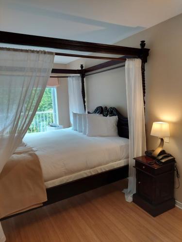 a bedroom with a canopy bed with a window at Studio-hôtel Villegiature Saint-Sauveur in Piedmont