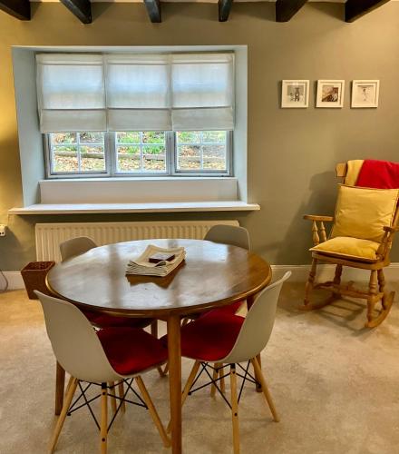 a table and chairs in a room with a window at Elyvale Cottage in the heart of Rothbury in Rothbury