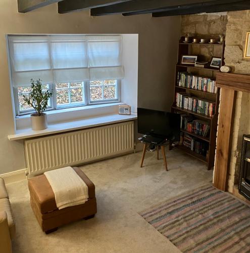 a living room with a television and a window at Elyvale Cottage in the heart of Rothbury in Rothbury