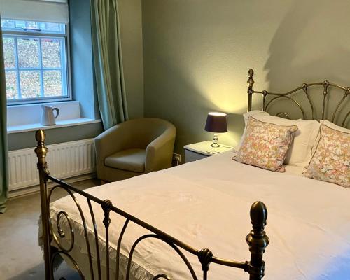 a bedroom with a bed and a chair and a window at Elyvale Cottage in the heart of Rothbury in Rothbury