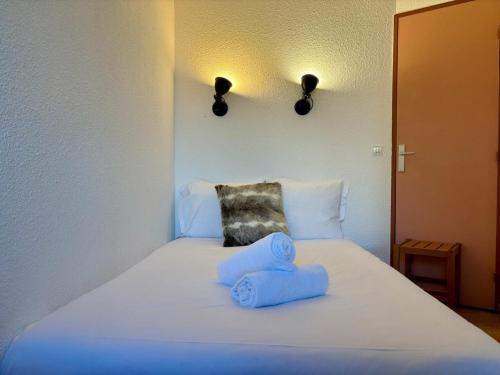 - un lit blanc avec 2 serviettes bleues dans l'établissement Le Chamois Blanc, à Chamonix-Mont-Blanc