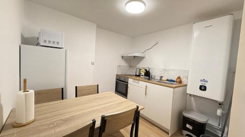 une petite cuisine avec une table et un réfrigérateur dans l'établissement Le carmes - Rétroprojecteur - Hypercentre Orléans, à Orléans