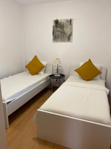 two beds in a white room with a side table at Casa Sylvia in Algeciras