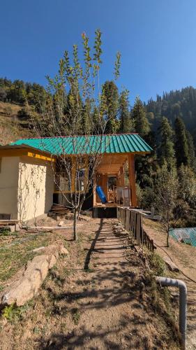 a small building with a green roof on a hill at Monkstel Cottages Shangarh in Shangarh