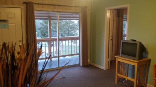 a living room with a television and a sliding glass door at Lodge At Turkey Cove in Canyon Lake