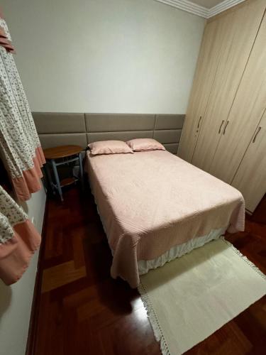 a bedroom with a bed with pink pillows on it at Apartamentos Centrinho Capivari - Recanto Boticário in Campos do Jordão