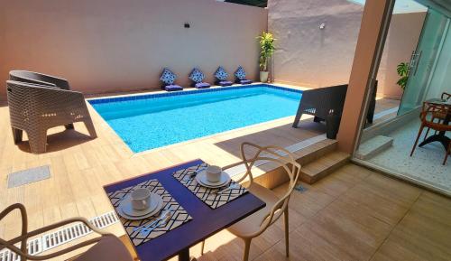 a swimming pool with a table and chairs next to it at Pousada Noa in Cabo Frio