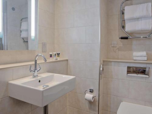 a white bathroom with a sink and a shower at Sunday Box Hill Burford Bridge Hotel in Dorking