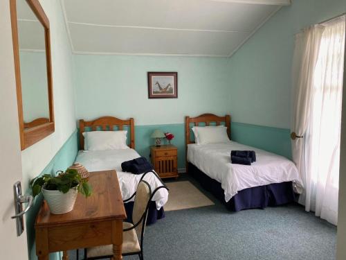 Cette chambre comprend 2 lits, une table et une table. dans l'établissement Mvemve Lodge at GrootPoort, à Memel