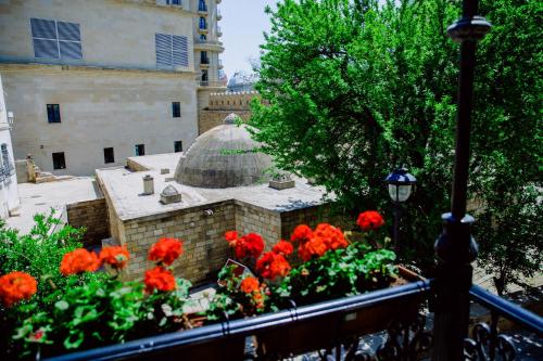 a garden with red flowers and a building at Royal Garden Hotel in Baku
