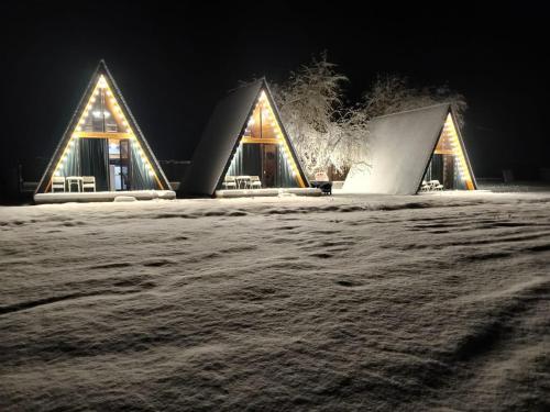 a couple of buildings in the snow at night at Kvabtkari Cottages in Ambrolauri