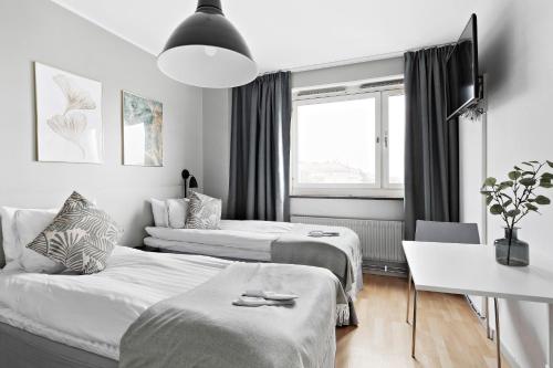 a hotel room with two beds and a table at Forenom Hotels & Apartments Stockholm Alvik in Stockholm