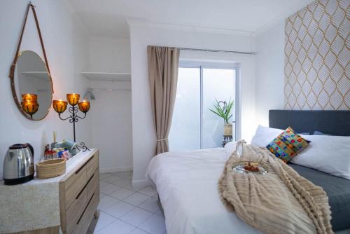 a bedroom with a bed with a dresser and a mirror at Cosy and Central in Claremont in Cape Town