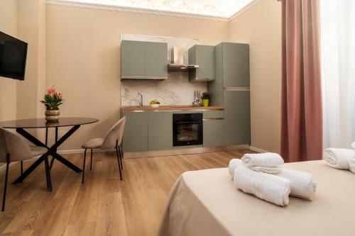 a room with two beds and a table and a kitchen at Archimedes suites in Catania
