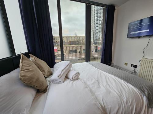 a bedroom with a bed with towels and a large window at Penthouse - Whitechapel in London