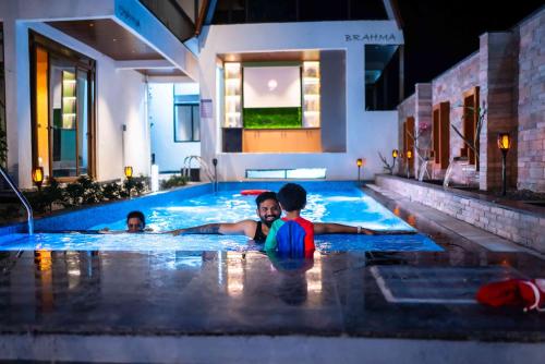 two children are swimming in a swimming pool at Amara Kosha Misty Hills - Skanda in Nandi