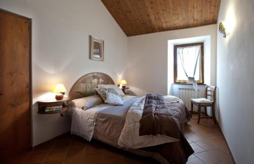a bedroom with a bed and a window and a chair at Fonte Al Noce in Gubbio