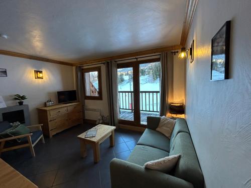 ein Wohnzimmer mit einer grünen Couch und einem Fernseher in der Unterkunft L’Aster in Lanslebourg-Mont-Cenis