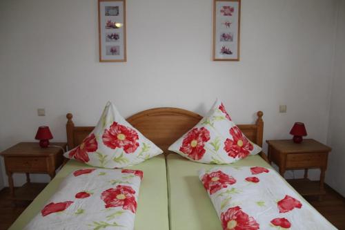 a bed with two red and white pillows on it at Pension & Ferienwohnung Breitmoser Angelika in Riedenburg