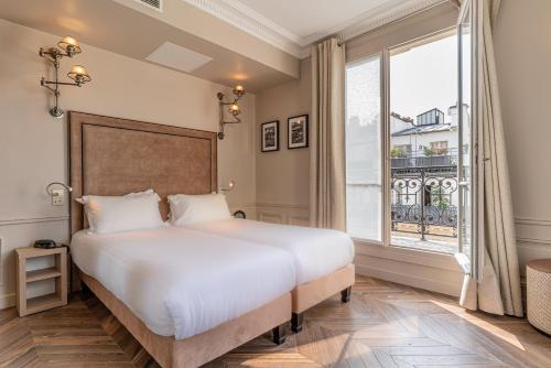 a bedroom with a large bed and a large window at Hôtel Perreyve - Jardin du Luxembourg in Paris