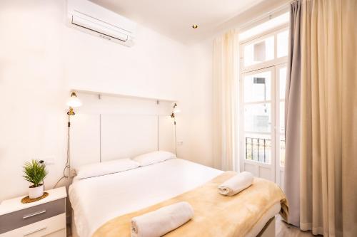 a white bedroom with a bed and a window at Main Street Suite & Views , by CartagenaSpain in Cartagena