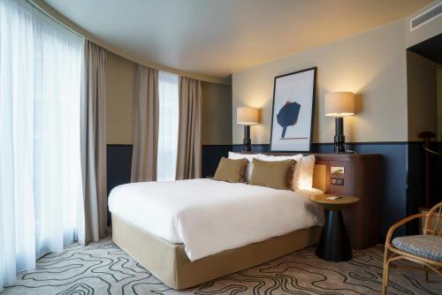 a hotel room with a large bed and windows at voco Paris - Porte de Clichy by IHG in Clichy