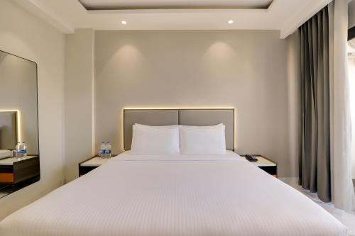 a bedroom with a large bed with white sheets at The Hoften Sukh Vasa, Sector 51 & Golf Course Ext Road in Gurgaon