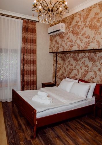 a bedroom with a bed with white sheets and a chandelier at Royal Garden Hotel in Baku