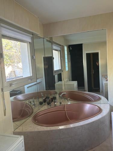 La salle de bains est pourvue de 3 lavabos bruns et d'un grand miroir. dans l'établissement Escapade, à Sète