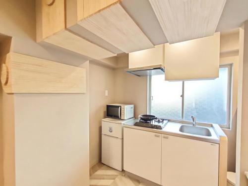a small kitchen with a sink and a microwave at 26 新宿中心2卧室 超级商圈 交通枢纽 早稻田大学 东新宿车站8分钟 最大5人 Shinjuku center 8 mins to ST 5P Maxs 直达新宿 涉谷 表参道 品川 池袋 上野 代代木 银座 原宿 in Tokyo