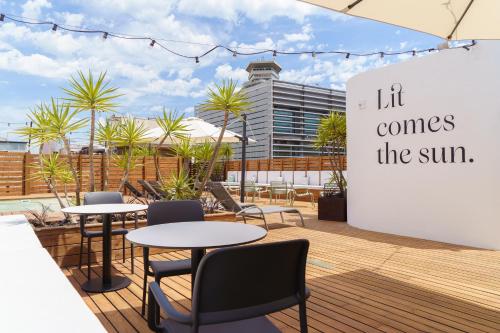 a patio with tables and chairs and a sign that reads lift comes the sun at Casa Lit Barcelona in Barcelona
