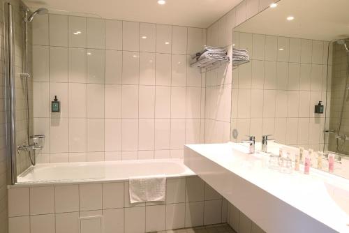 a bathroom with a tub and a sink and a mirror at Comfort Hotel Porsgrunn in Porsgrunn